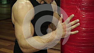 Young sweaty boxer is resting on punching bag