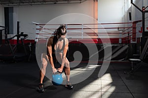 Young sweaty muscular active woman athlete heavy kettlebell workout crossfit hardcore training in the gym. Strong female exercise