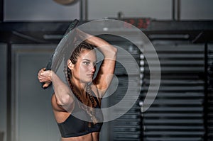 Young sweaty muscular strong fit girl holding big heavy barbell weight plate with her hands and circling around her head as hardco