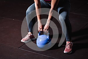 Young sweaty strong muscular fit girl hands holding heavy kettlebell on the floor concentrating and preparing for hardcore cross s