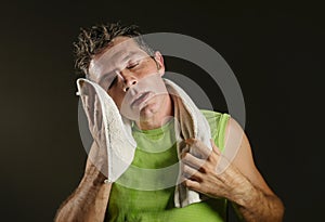 Young sweaty tired and exhausted sport man drying sweat after hard fitness workout at gym club isolated on black background in