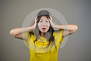 Young sweet and beautiful Asian Korean woman gesturing shocked and surprised as if oh my god what a disaster in astonished face ex