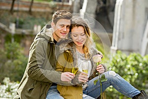 Young sweet couple in love kissing tenderly on street celebrating Valentines day or anniversary cheering in Champagne
