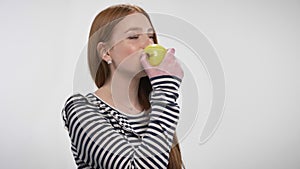 Young sweet ginger girl is biting apple, offer it, communication concept, white background