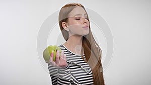 Young sweet ginger girl is biting big apple, enjoying it, offering, communication concept, white background