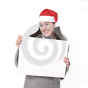 Young sweet Latin woman in Santa Christmas hat holding blank billboard