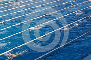 Young swimmers in outdoor swimming pool during freestyle race. Health and fitness lifestyle.