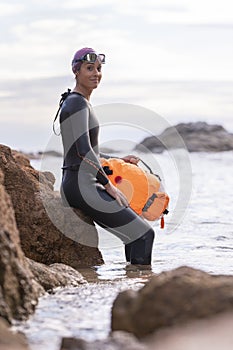 Young swimming woman about to enter the sea looking to the camera