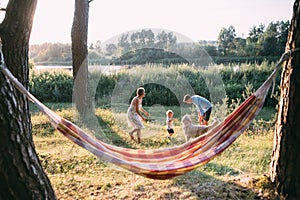 Young sympathetic family - mom, dad and son rest in nature, near a hammock