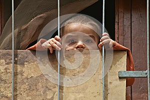 Young Syrian boy looks through the fence of his house in Homs