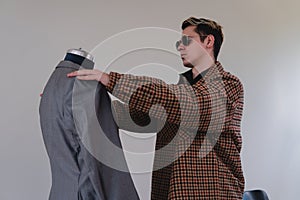 A young tailor preparing a new suit. A costume designer working on a mannequin. Tailor measuring a gray suit.