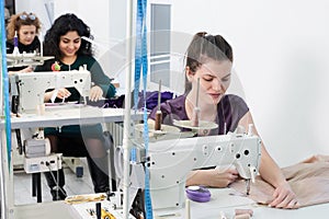 Young tailors sew clothes on sewing machine in atelier studio