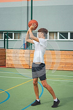 Young talented basketball player is shooting hoops on his outdoor court and training for future games and tough situations.