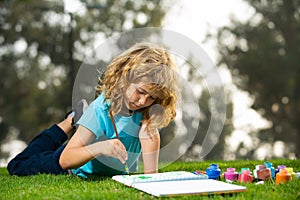 Young talented boy artist painter. Schooler kids drawing in summer park, painting art. Little painter draw pictures