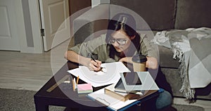 Young talented female artist drawing pencil sketches sitting on the floor in the evening at home. Designer or Illustrator working