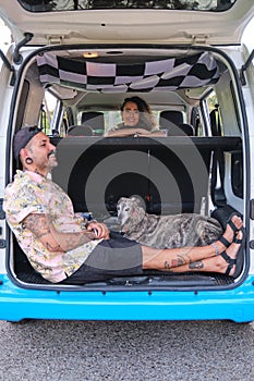 Young tattooed couple smiling with their dogs sitting in the back of the van.