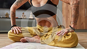 Young tattooed girl practicing abdominal lock at home