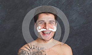 Young tattooed man with moustaches from foam