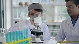 Young teacher and boy use microscope in science class at laboratory