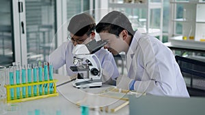 Young teacher and boy use microscope in science class at laboratory