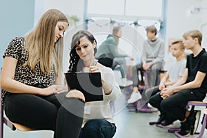 Young teacher checks the attendance list during additional workshops at school