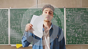 Young teacher fanning paper sheets in a very hot classroom