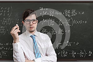 Young teacher in front of blackboard with math equations