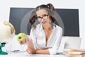 young teacher with green apple sitting at workplace