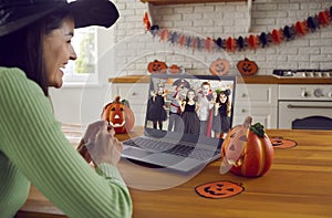 Happy woman in front of computer screen having online Halloween party with children