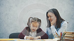 Young teacher helping child writing lesson or mother and daughter learning to write, mother teaching little girl