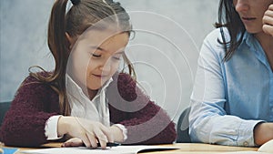 Young teacher helping child writing lesson or mother and daughter learning to write, mother teaching little girl