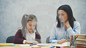 Young teacher helping child writing lesson or mother and daughter learning to write, mother teaching little girl