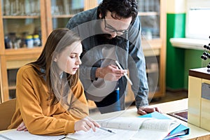 Young teacher helping his student in chemistry class. Education and Tutoring concept.