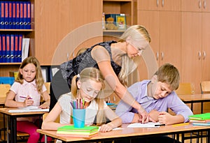 Young teacher helps students of primary school in the exam