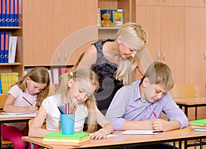 Young teacher helps students of primary school in the exam