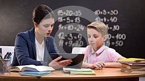 Young teacher showing schoolboy information on tab, private lesson, innovations