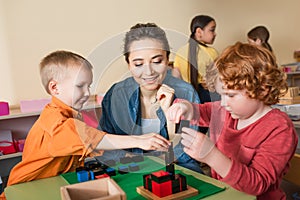 young teacher smiling near boys playing