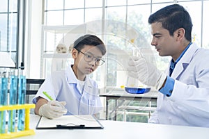 Young teacher and student boy use microscope in science class at laboratory