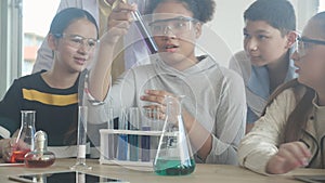 Young teacher teaching group student about science and explaining chemical for liquid in the lab of school.