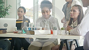 Young teacher teaching group student about science and explaining chemical for liquid in the lab of school.