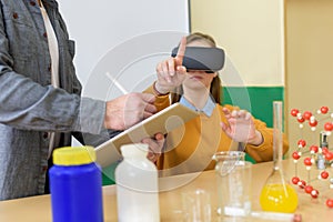 Young teacher using Virtual Reality Glasses and 3D presentation to teach students in chemistry class.Education, VR, New technology