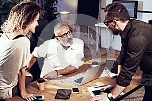 Young team of coworkers making great work discussion in modern coworking studio.Bearded man talking with colleagues
