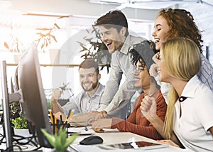 Young team of excited coworkers celebrating in office