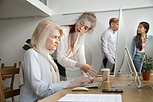 Young team leader correcting offended senior employee scolding f