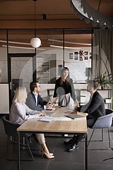 Young team manager woman talking to business colleagues at table