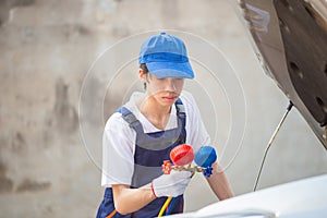 Young technician check car air conditioning system refrigerant recharge, Repairman holding monitor tool to check and fixed car air