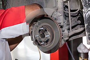Young technician fixing brake disk in car garage