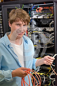 Young technician holding optical cable in datacenter