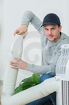 Young technician installing air conditioning system indoors