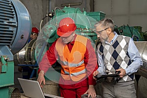 Young Technician with Laptop Computer Checking Data With Technical Manager in Mechanical Room